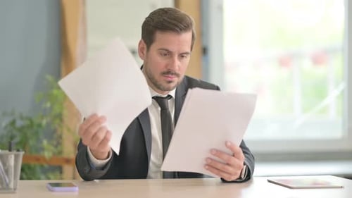 Man Reviews Documents at His Office Desk