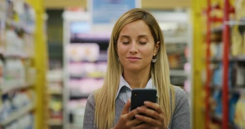 Authentic close up shot of happy smiling young woman is using a smartphone for online store applic