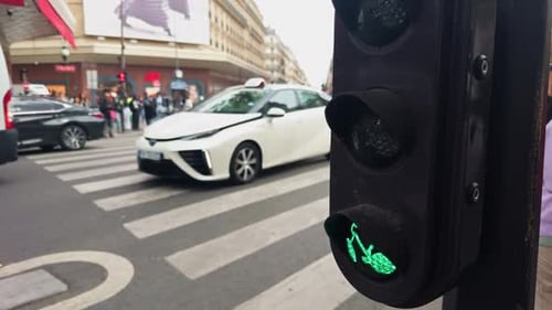 Uma faixa de pedestres urbana com um sinal verde para pedestres enquanto um veículo passa pelo