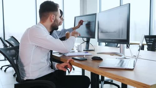Grafiken auf einem Smartphone-Bildschirm. Zwei Mitarbeiter arbeiten zusammen im Büro.