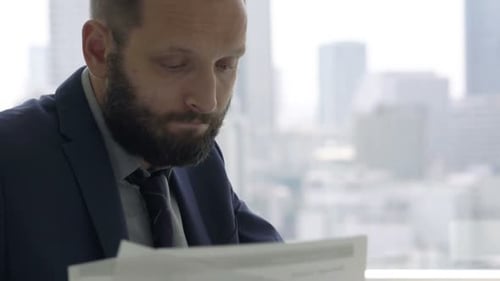 Overworked businessman struggles with documents and laptop in modern city office