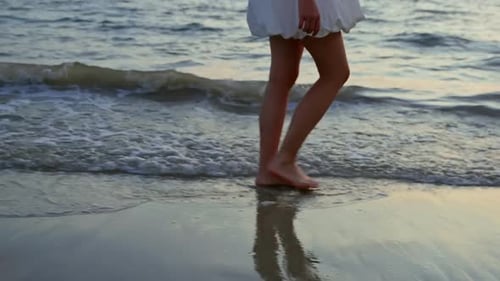 Close Up of Woman Legs Walking Barefoot on Beach with Ocean Waves Splashing
