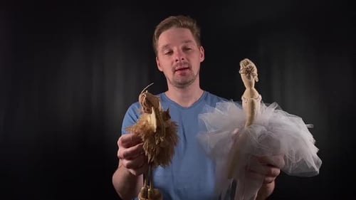 A Portrait of a Handsome Young White Man Holding Puppets Playing with Them Depicting a Puppeteer