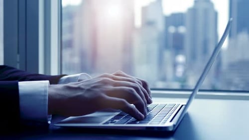 Man Typing on Laptop in Modern Office