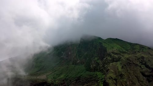 Aerial View of Lush Green Mountain Ridge Covered in Thick Mystic Fog and Low Clouds in Nature