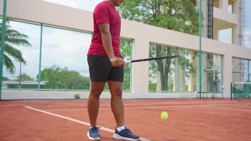 Asian young sportsman exercise, playing tennis on outdoor clay court.