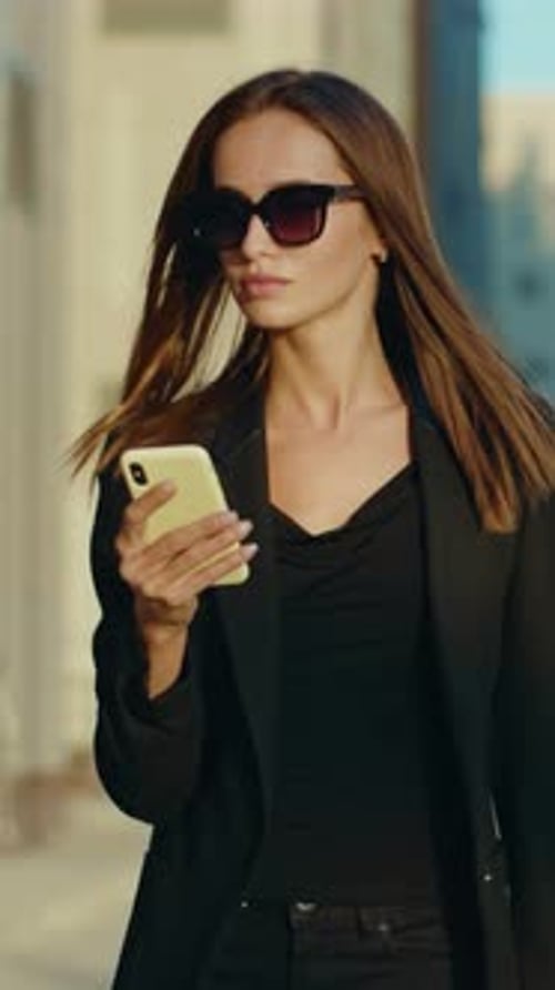 Young Woman Walking with Phone in Urban Setting