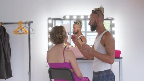 AfricanAmerican Gay Man Applying Makeup for Woman in Studio