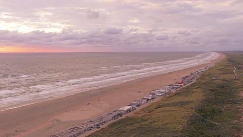 Weite Luftaufnahme des Strandes und der Dünen von Wijk aan Zee, die zur Sonnenuntergangsstunde leuchten