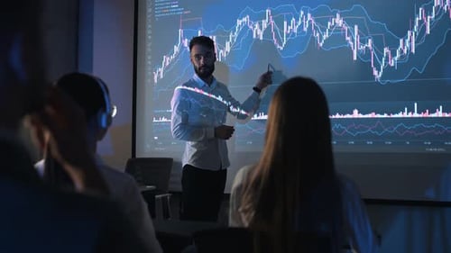 Presenter Explains Financial Graph to Colleagues in Dark Office