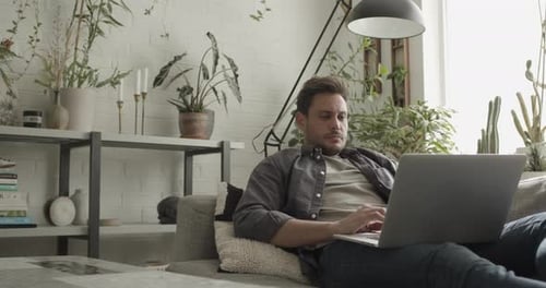 Man Relaxing on Couch While Working on Laptop