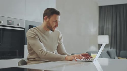 Man Working on Laptop at Modern Kitchen Counter