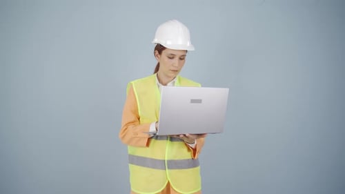 Ingenieur hält Laptop und lacht in die Kamera.