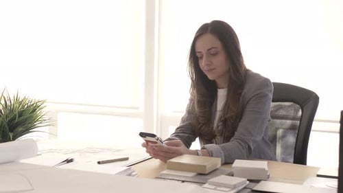 Professional woman at desk working on smartphone