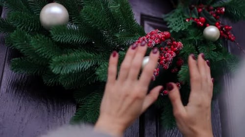 Adjusting Christmas Wreath with Ornaments and Berries