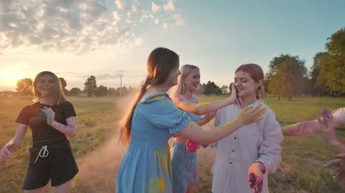 School Friends Sprinkled with Colorful Powders at Sunset