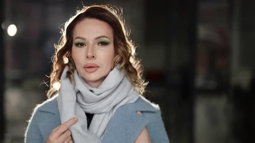 Beautiful Adult Woman Wrapping in Scarf and Coat Standing on City Street in Evening Portrait