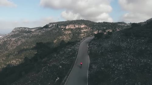 Cyclist in protective helmet and pink jersey riding uphill on bicycle