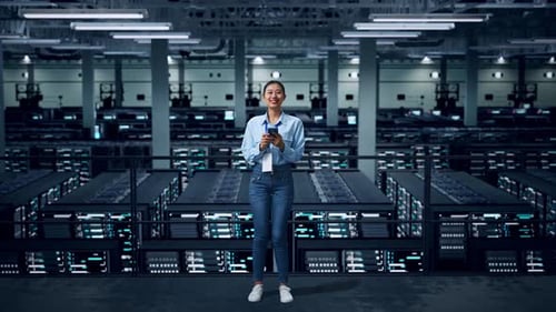 Full Body Of An Asian Business Woman Using Mobile Phone And Smiling To Camera In Data Center