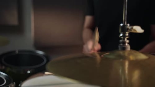 The Drummer Hits the Hihat with a Drumstick Making a Loud Sonorous Sound The Drummer is Wearing a