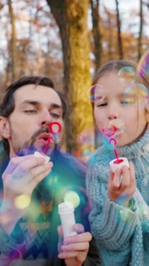 Young Dad in Casual Clothes and Little Daughter Blowing Soap Bubbles Which Flying on you They