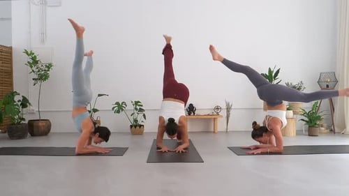 Trois femmes yogis faisant la pose du scorpion dans un studio de yoga