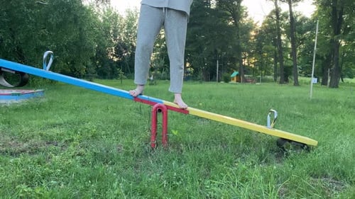 Barefoot Female Person Finds Equilibrium on Playground Outdoors