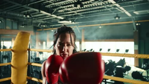 Determined Woman Boxer Training Punches on Boxing Bag in an Urban Gym Environment