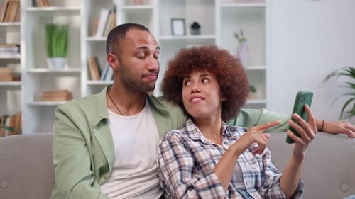 Relaxing Couple Using Smartphone on Couch Indoors