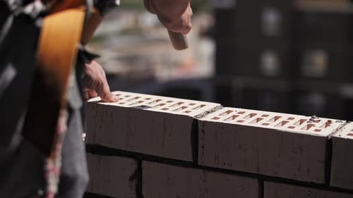 A Builder Lays Bricks at a Construction Site