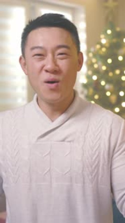 Smiling Man in Cozy Sweater near Christmas Tree