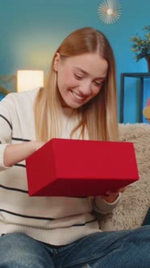 Woman Excitedly Opens Birthday Gift in Cozy Home