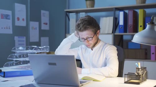 Man Works Late at Desk in Office