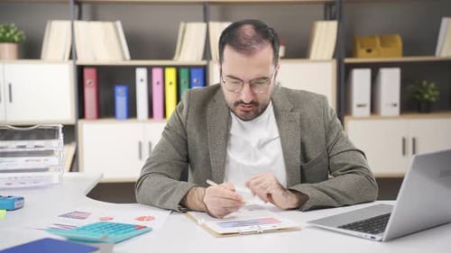 Man Working at Desk, Focused on Writing Task