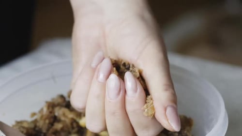 Eine Frau rührt den Teig mit Erdnüssen und Schokoladenstücken um. Mit einem Löffel in einem Behälter umrühren