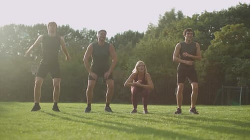 sporty family doing jump squats outdoors on grass