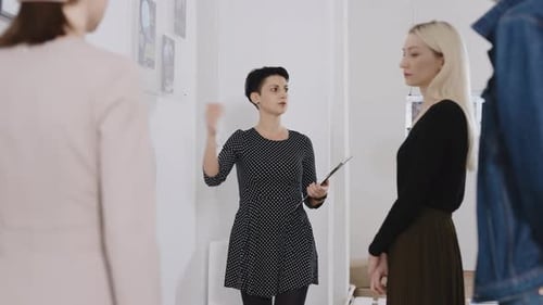 A Woman Gallery Owner Tells Visitors About the Paintings Presented at the Exhibition