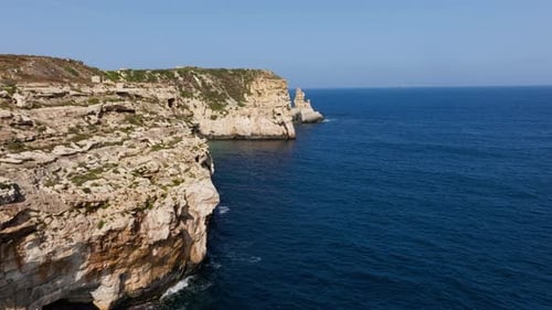 Aerial view flying along the steep, rocky coastline of sunny Malta island