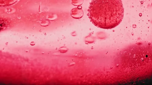 Makroaufnahme von funkelnden roten Blasen, die in leuchtend rotem Wasser zu Boden fallen
