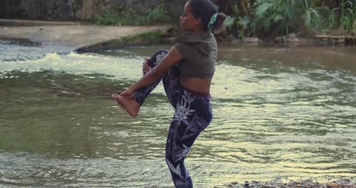A serene scene of a woman doing yoga at a riverside in the Caribbean.