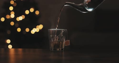 Pouring hot water with teapot. cristal glass. Herbal infusion. Christmas background. Cozy living roo