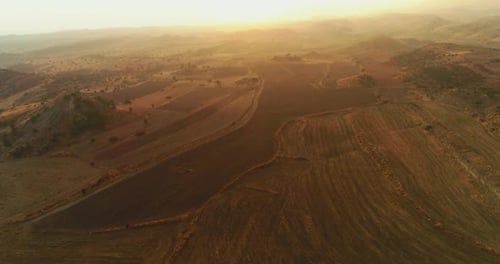 the drone is flying over the fields into the sunset. Aerial view of fields at sunset. 4K.