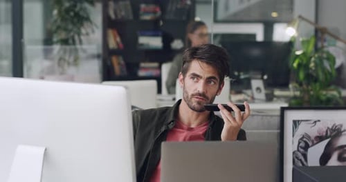 4k video footage of a young businessman using a smartphone and computer in a modern office