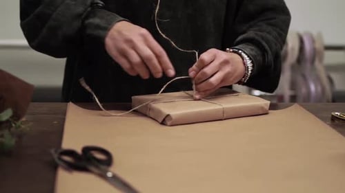 Hands Tying Twine on a Wrapped Gift