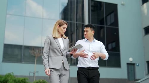 two employees partners walking along the street near the office business center, talking. team