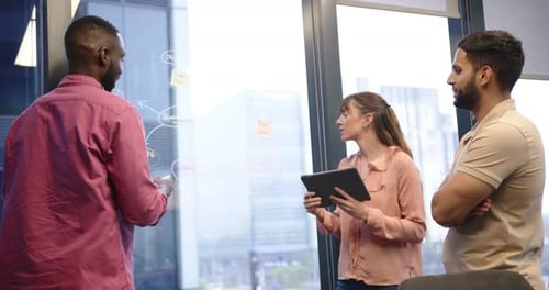 Discussing project strategy, team collaborating with tablet and whiteboard in office