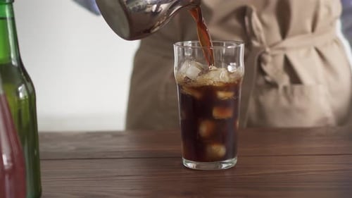 Pouring Coffee into Glass with Ice Cubes