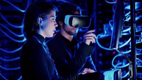 Woman programming in a server room while a man is using a Virtual Reality headset