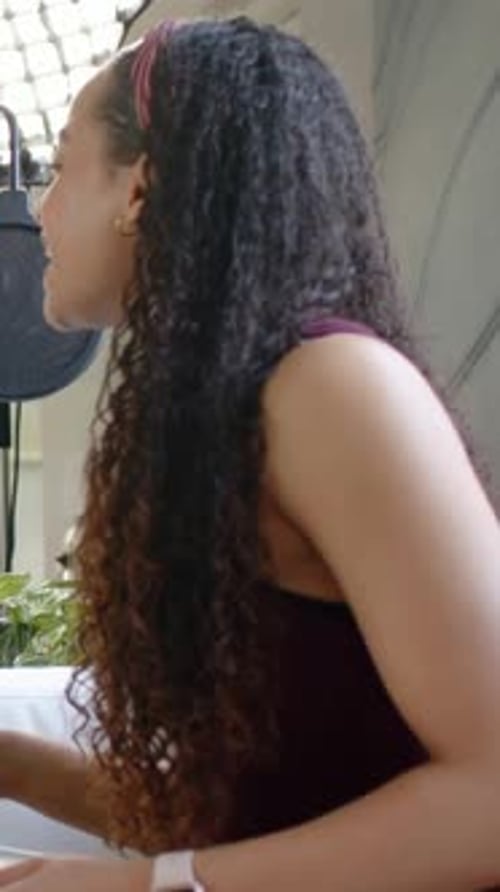 Vertical video: Leaning host recording into mic as softbox appearing in studio, maroon top headband