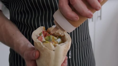 Chef Saucing Pita Pocket Sandwich Close Up